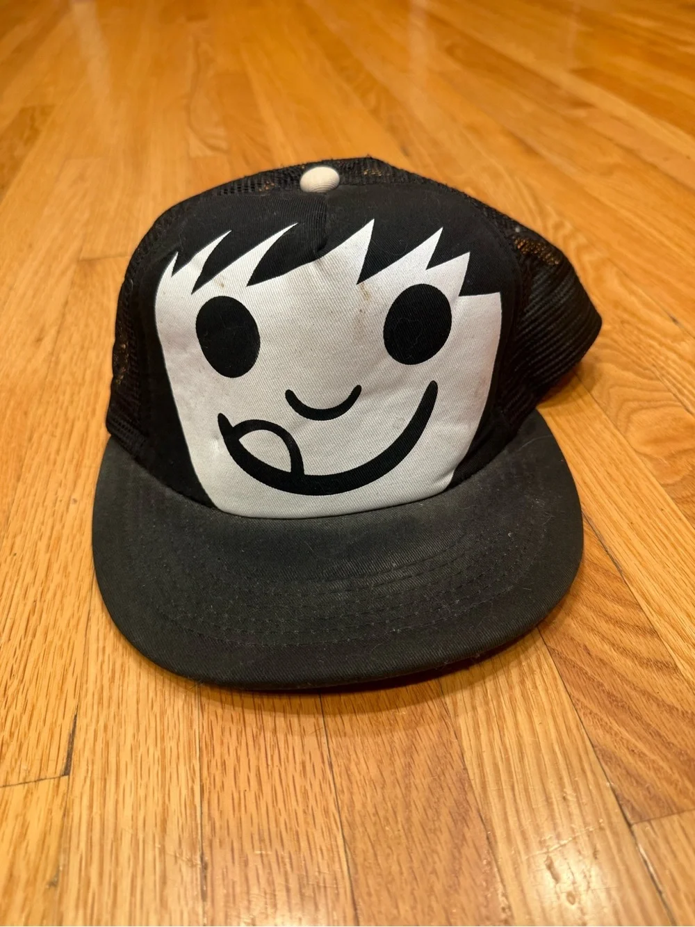 Sucka Character Black Trucker Hat with Playful White Face Graphic